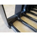 Close-up of black painted steel manure tine attachment with tubular tines welded to a rectangular frame on concrete floor