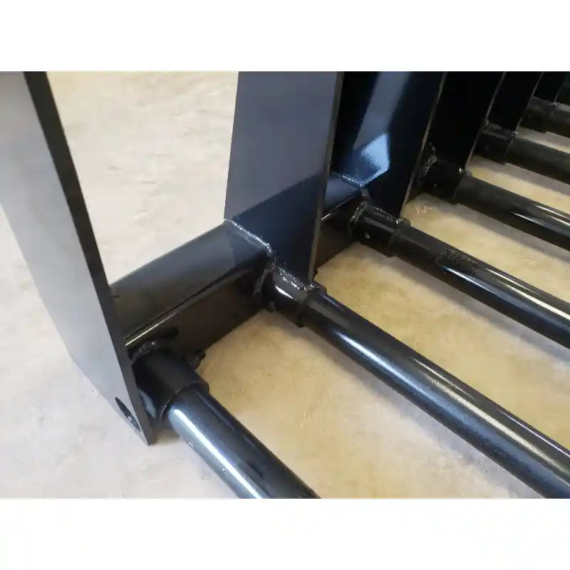 Detail of black painted tubular steel tines welded to a reinforced support frame on concrete floor indoors