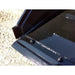 Close-up of black steel skid steer bucket edge with welded reinforcements and heavy mounting bolts on gravel surface