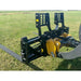Black steel pallet fork attachment with perforated backrest mounted on yellow skid steer arm on grass field