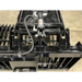 Close-up of black steel skid steer rock grapple attachment with hydraulic cylinder, hoses, and reinforced mounting bracket on concrete floor