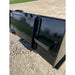 Rear view of black steel skid steer material bucket with step attachment and reinforced welds on gravel surface