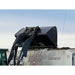 Close-up of black skid steer high-volume bucket attachment lifting loose soil above a dump truck outdoors