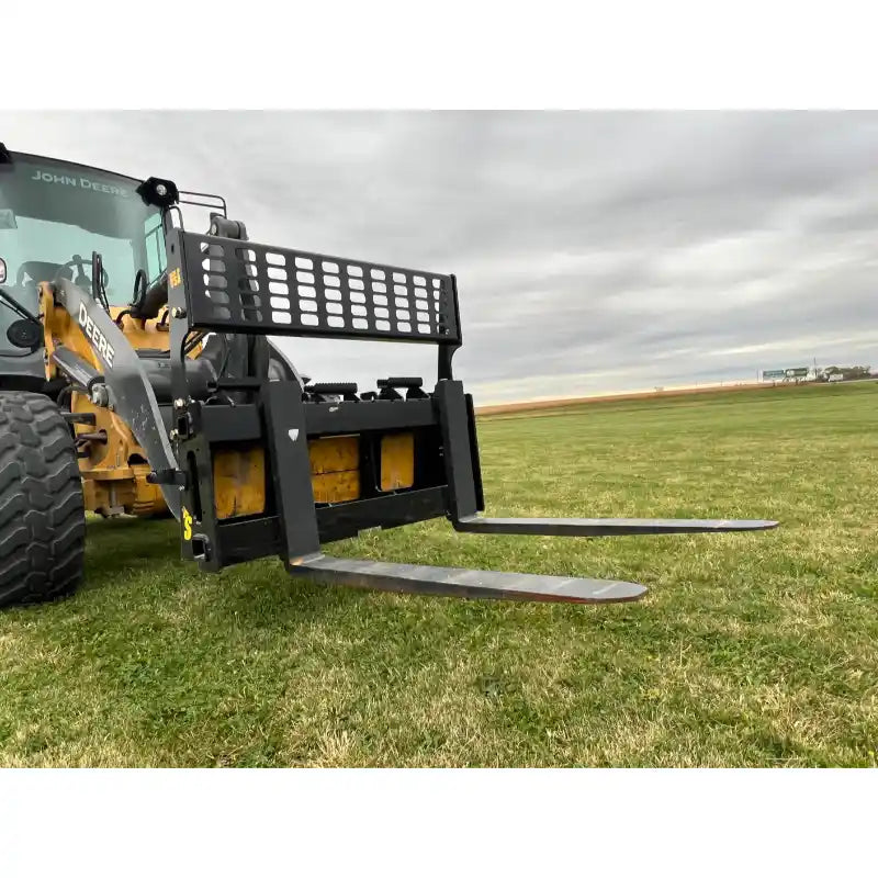 Black skid steer pallet fork attachment with perforated backrest and two extended steel tines on grassy field