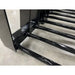 Close-up of black metal grapple attachment tines with spear-shaped ends and reinforced welds on concrete floor indoors