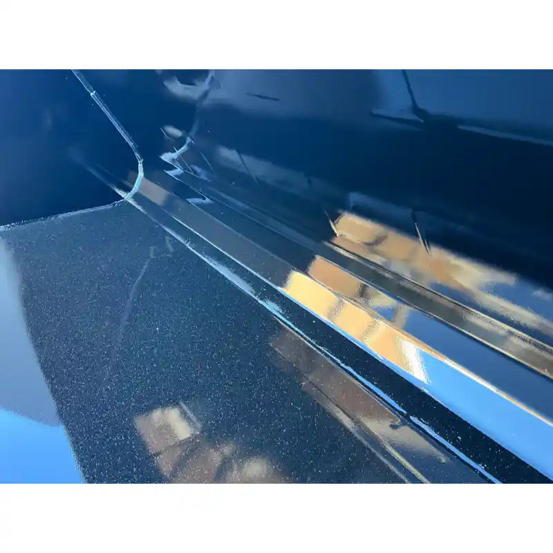 Close-up of smooth black steel interior surface showing weld seams and reflections on a liquid slurry bucket attachment