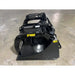 Black steel demolition grapple bucket attachment with hydraulic cylinders and curved clamp arms on concrete floor indoors
