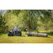Man on ATV towing Swisher log skidder moving large log across grassy field, gallery position 1