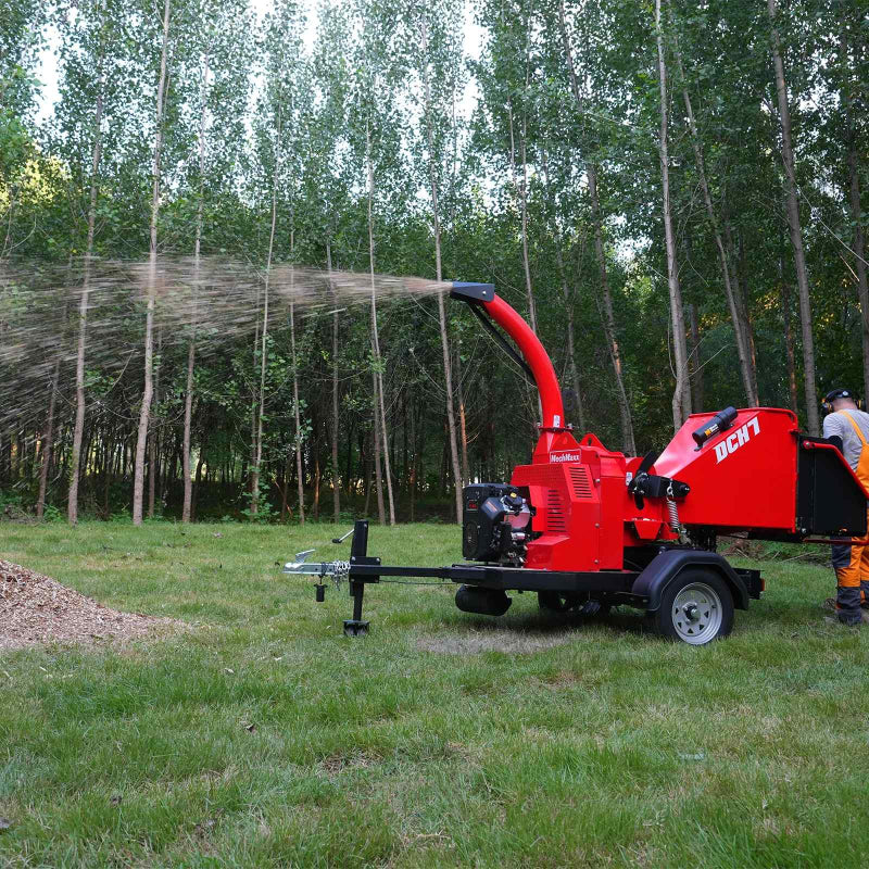 Side view of red MechMaxx 7-inch hydraulic feed wood chipper operating and ejecting wood chips, gallery position 1
