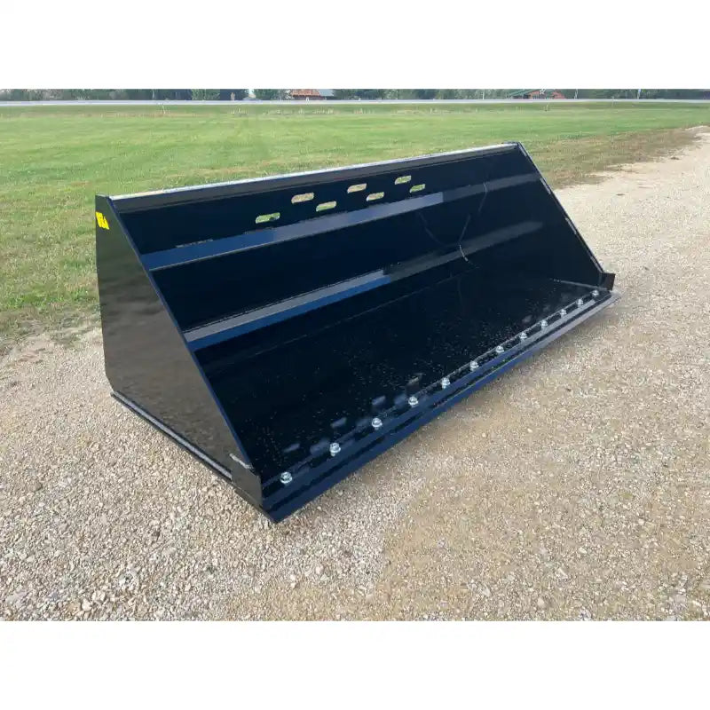 Black metal skid steer snow bucket attachment with bolt-on cutting edge and rectangular ventilation slots on gravel surface