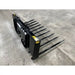 Black steel manure spear attachment with ten long tines and mounting bracket on concrete floor indoors
