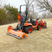 Rear view of orange MechMaxx 60-inch PTO driven light-duty flail mower attached to compact tractor, gallery position 1