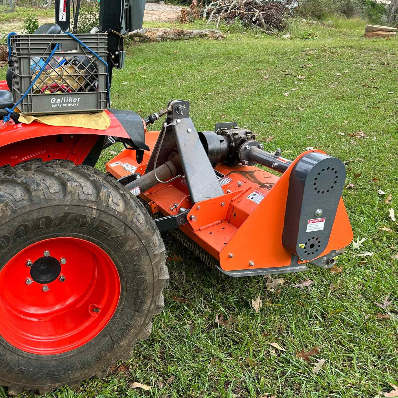 Close-up right side of orange MechMaxx 60-inch PTO driven flail mower attached to tractor, gallery position 1