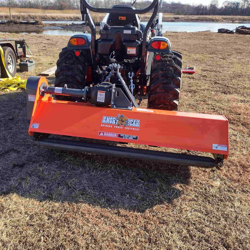 Rear view of orange PTO flail mower attached to tractor showing driveline and roller, gallery position 1