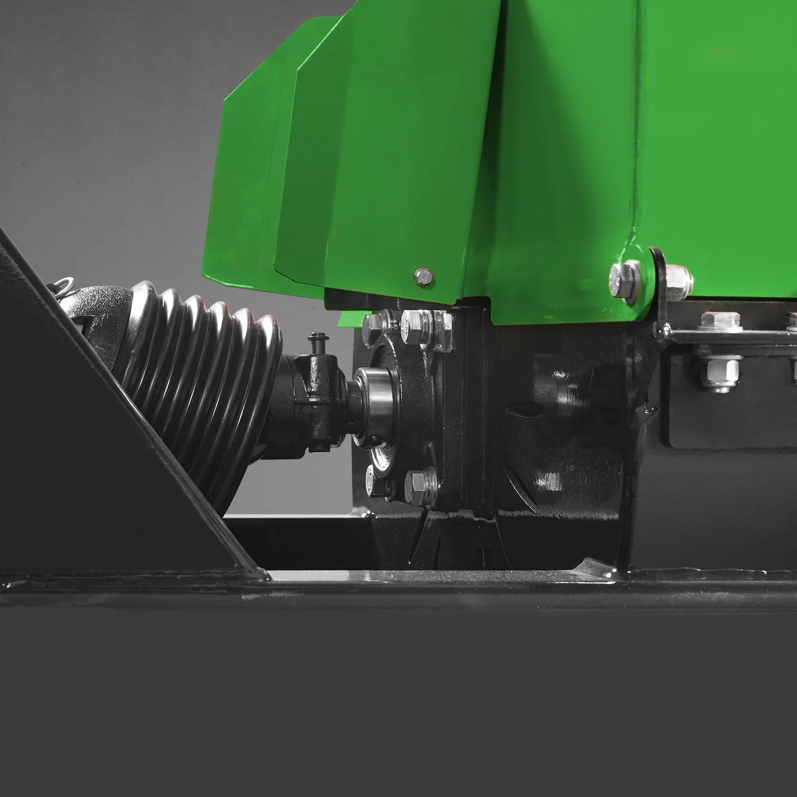 Close view of green PTO equipment housing with black gearbox, drive shaft, and mounting bolts