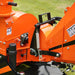 Orange PTO equipment housing with hydraulic hoses, belt guard, tension spring, and warning label