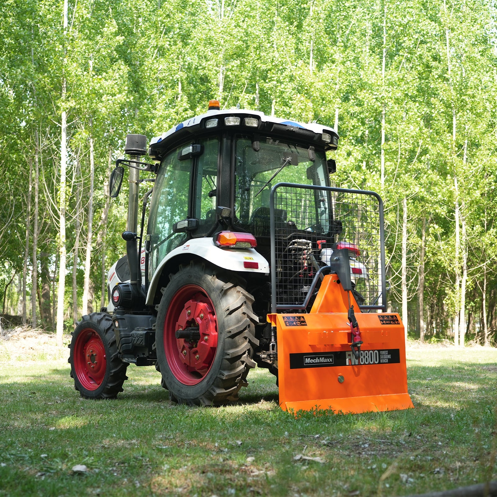White tractor with orange rear-mounted winch attachment, mesh guard, cable, and warning labels in a forest clearing