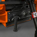 Orange equipment attachment with black mounting bracket, support leg, bolts, and hydraulic cylinder