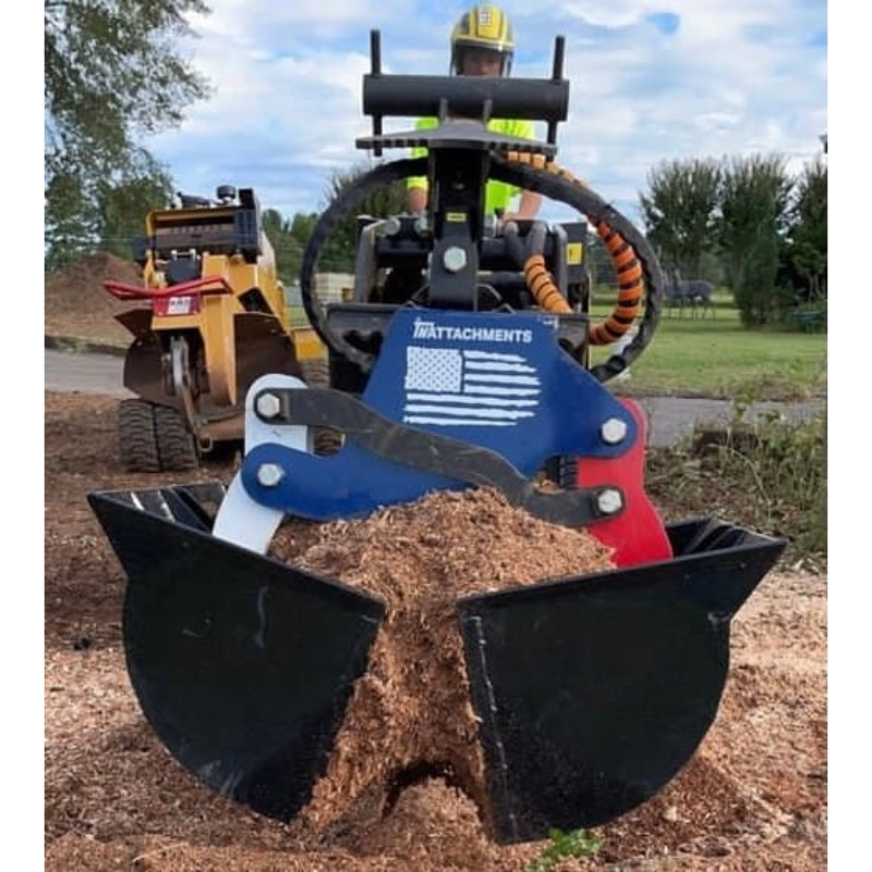 Black steel clamshell bucket attachment with wide scoops filled with mulch connected to a compact loader with hydraulic hoses