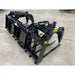 Black-painted metal manure grapple attachment with hydraulic cylinders and wide tines on concrete floor indoors