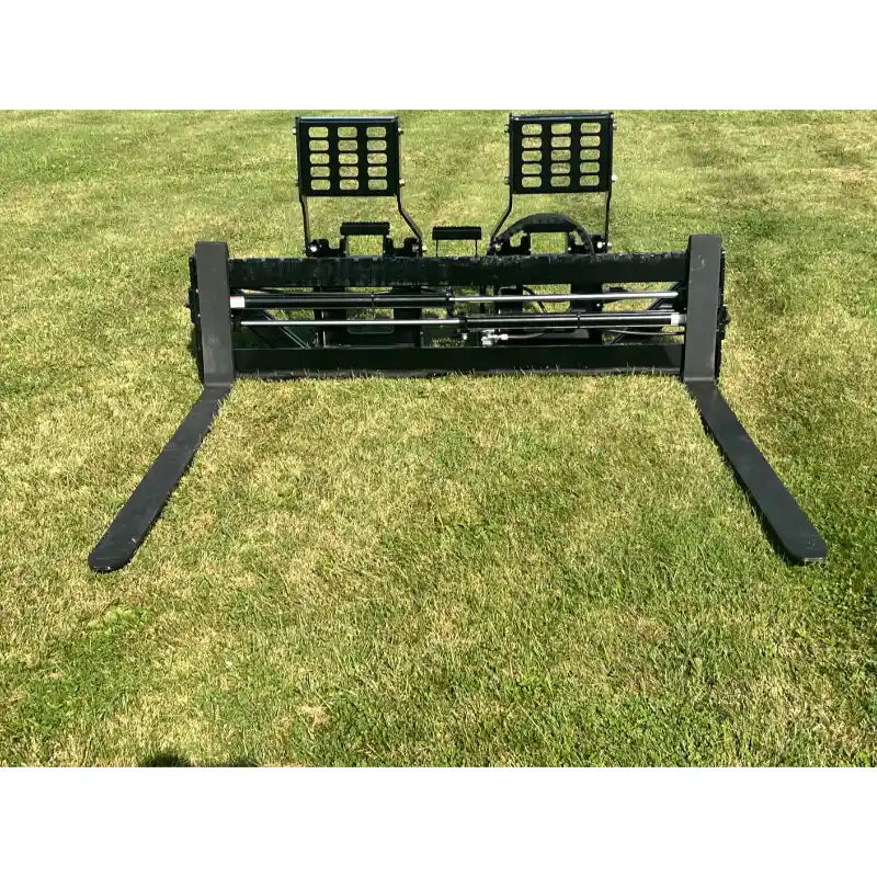 Black steel skid steer pallet fork attachment with dual adjustable backrests and long flat fork tines on grass field