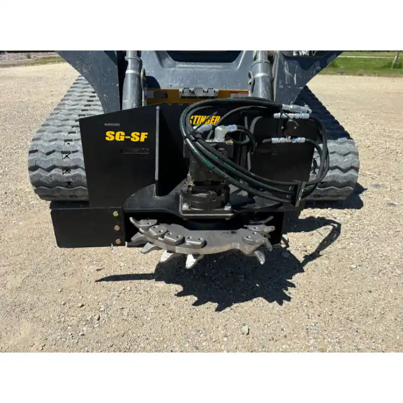 Stump grinder attachment with steel cutting wheel, multiple teeth, hydraulic hoses, and black mounting plate on compact tracked machine