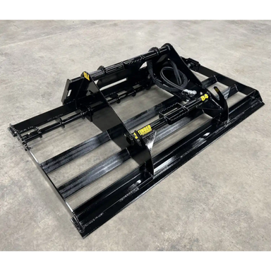 Black steel skid steer land plane attachment with hydraulic hoses on concrete surface