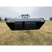 Front view of black steel hydraulic dump bucket attachment elevated in front of a tractor on grassy field