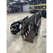 Two heavy steel clam grapple attachments stacked indoors on concrete floor with storage racks in background