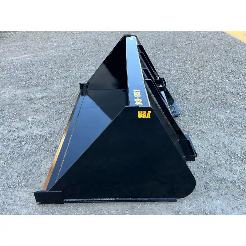 Black steel liquid slurry bucket attachment with angled sides and reinforced back resting on gravel surface outdoors