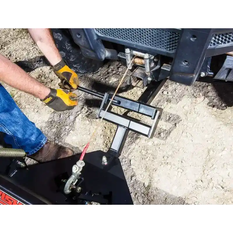 Man wearing gloves tightening steel mounting bracket connecting Swisher 62-inch UTV angle plow to vehicle, gallery position 1