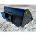Right side view of black steel skid steer bucket attachment resting on snow-covered gravel surface outdoors