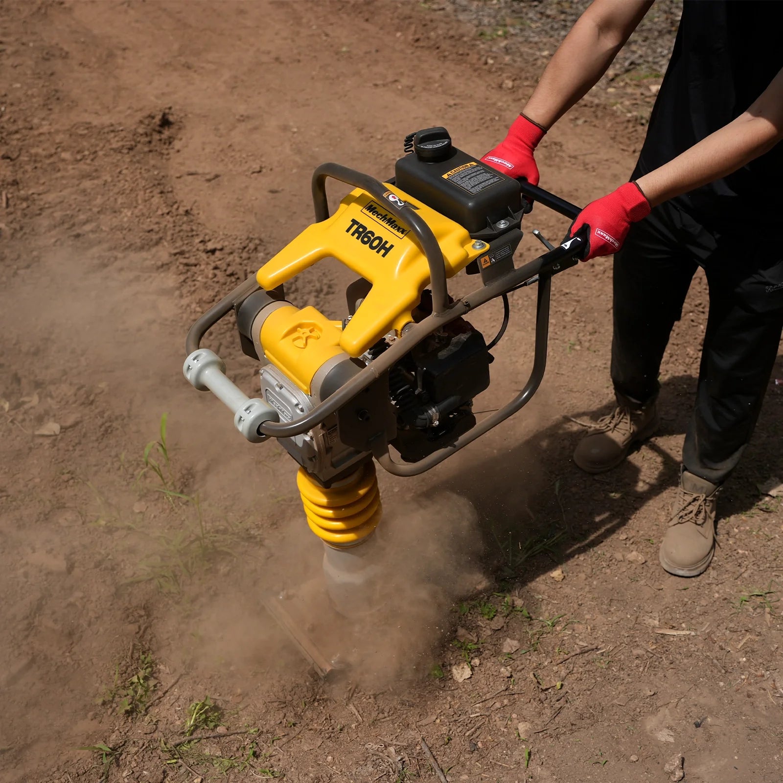Yellow vibratory rammer compacting soil as an operator holds the handle