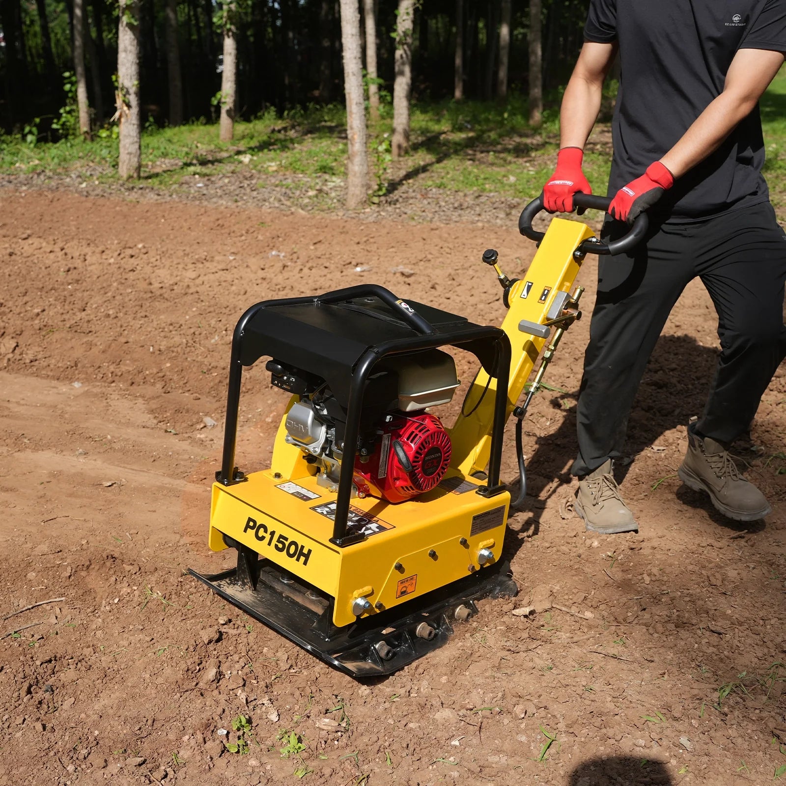 Yellow PC150H plate compactor with red engine, black protective cage, and operator handle on dirt worksite