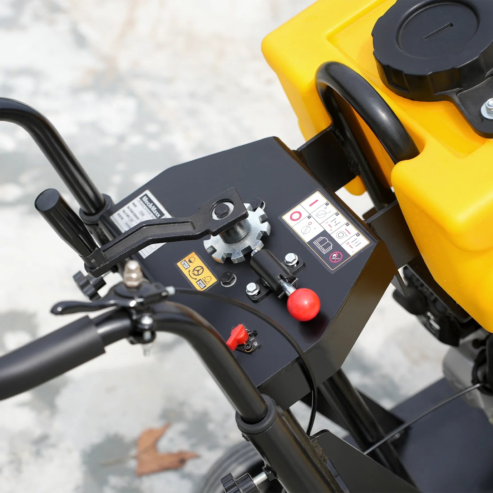 Close-up of yellow compactor control panel with black handles, red lever, fuel cap, and instruction labels