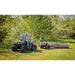 Operator on ATV pulling Swisher log skidder carrying large cut log across grassy clearing, gallery position 1