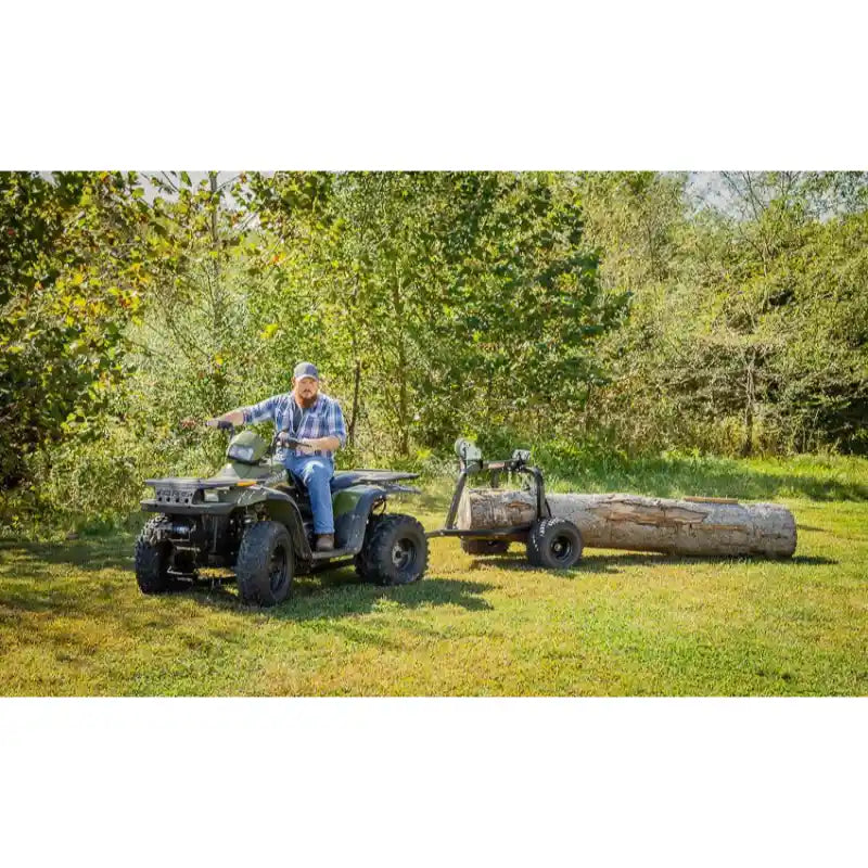 Operator on ATV pulling Swisher log skidder carrying large cut log across grassy clearing, gallery position 1