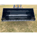 Black steel hydraulic dump bucket attachment mounted on front loader arm over grassy field