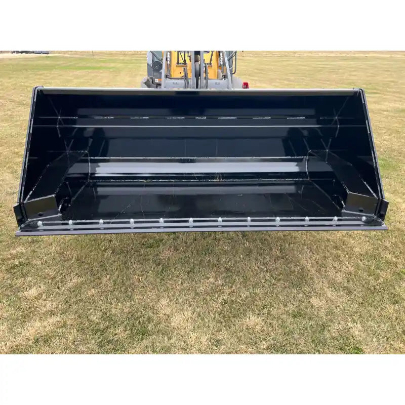 Black steel hydraulic dump bucket attachment mounted on front loader arm over grassy field