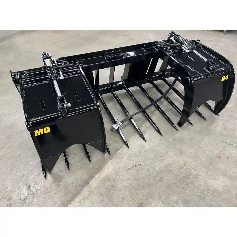 Black hydraulic manure grapple attachment with multiple pointed tines and reinforced frame on concrete floor indoors