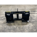 Black metal skid steer attachment with yellow Stinger branding on a concrete floor