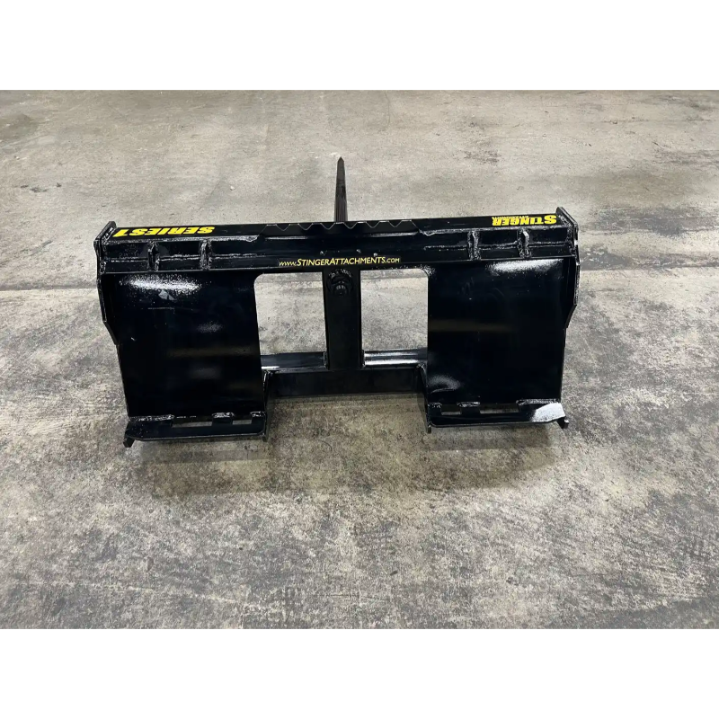 Black metal skid steer attachment with yellow Stinger branding on a concrete floor