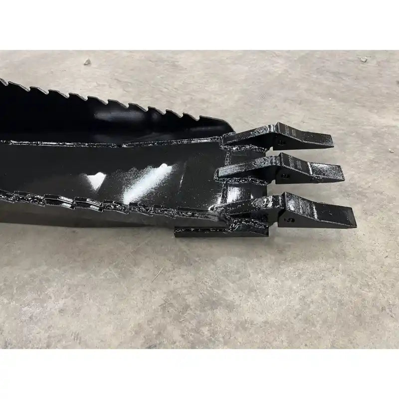 Black metal skid steer attachment bucket with three thick digging teeth and serrated cutting edge on concrete floor