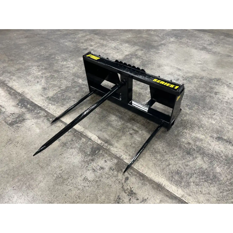 Black metal skid steer attachment with three pointed tines on a concrete floor, labeled Series 1