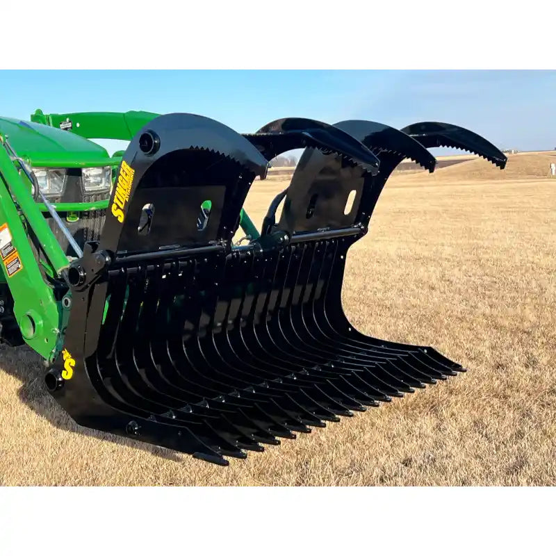 Black steel grapple attachment with serrated clamshell jaws and wide curved tines mounted on green tractor loader arm