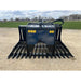 Front view of black metal skid steer rock grapple attachment with wide spaced curved tines and hydraulic hoses on gravel surface