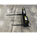 Black metal bale spear attachment with two long pointed spears on concrete floor
