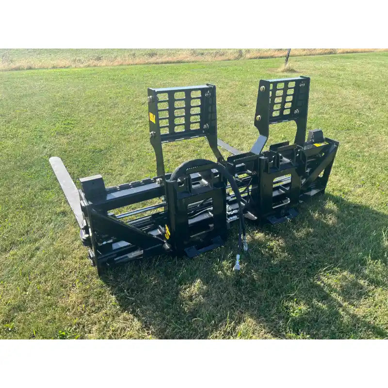 Black skid steer pallet fork attachment with two adjustable vertical backrests and dual flat fork tines on grass field