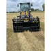 Front view of yellow John Deere loader equipped with large black steel clam-style grapple attachment on dry grass field