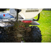 Close-up of Swisher ATV Commercial Pro Spreader mounting and material dispersing beneath ATV on grass, gallery position 1